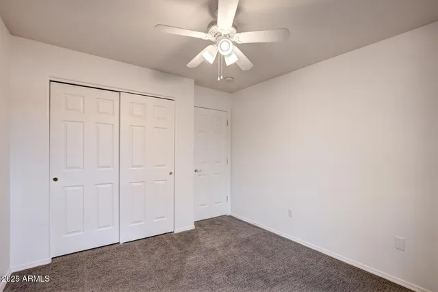 an empty room with a chandelier fan and closet area