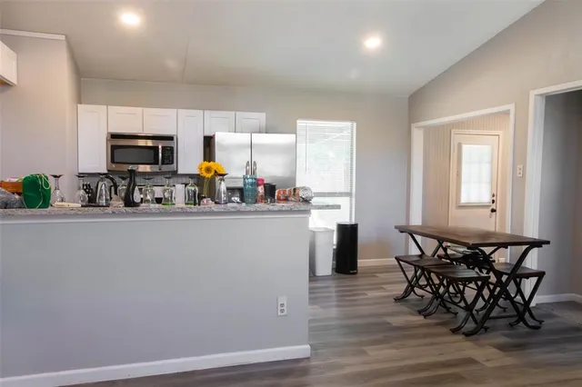 a kitchen with stainless steel appliances granite countertop a refrigerator a stove a sink dishwasher and a dining table with wooden floor