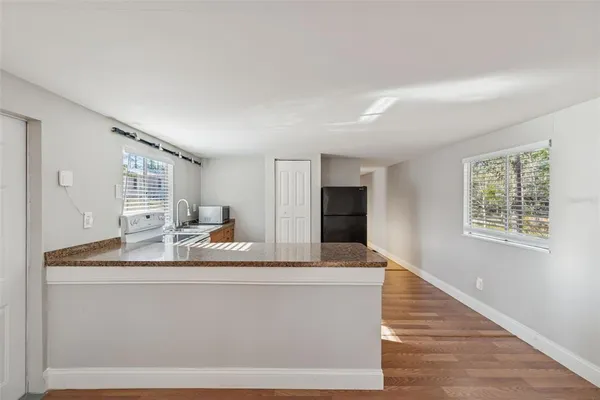 a room with kitchen island a sink wooden floor and window