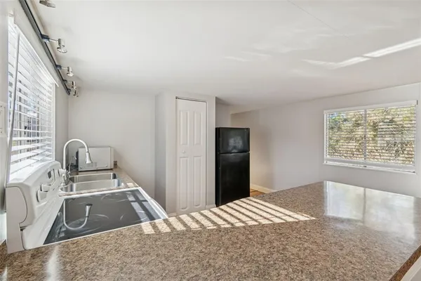 a kitchen with granite countertop a refrigerator and a stove top oven