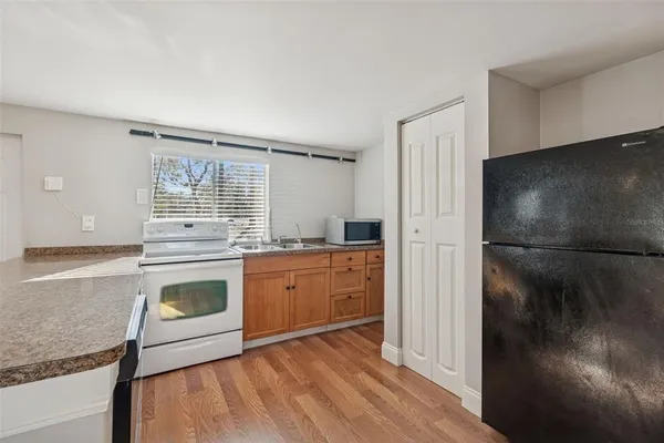 a kitchen with granite countertop a refrigerator stove top oven and sink