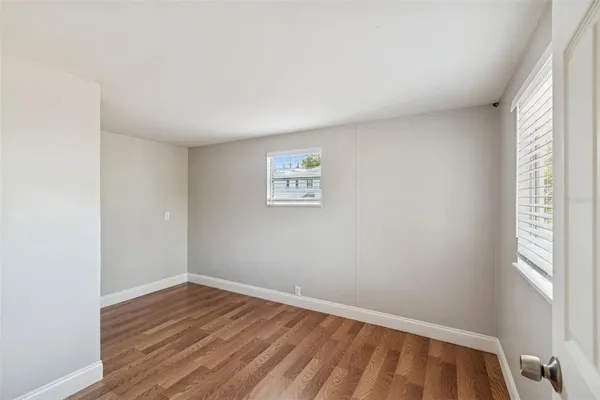 an empty room with wooden floor and window