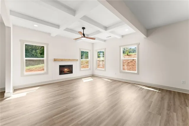 an empty room with windows fireplace and wooden floor