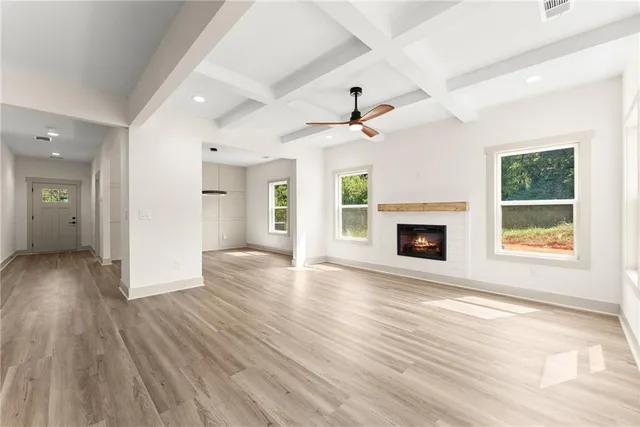 a view of an empty room with wooden floor fireplace and a window