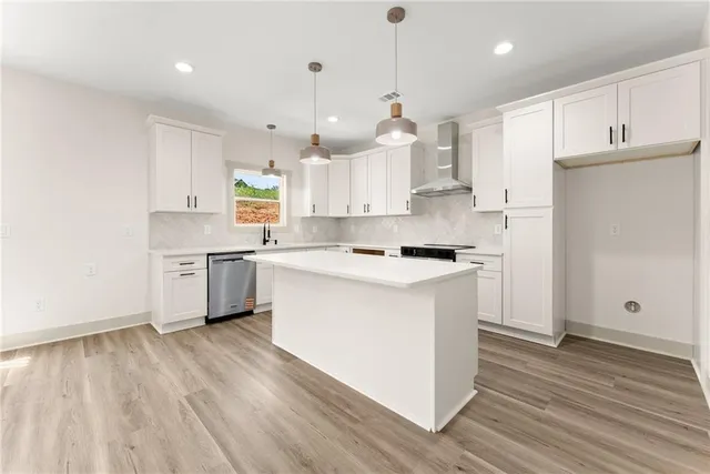 a kitchen with stainless steel appliances white cabinets a sink a window and wooden floor