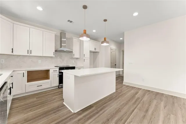 a large kitchen with stainless steel appliances granite countertop a stove a sink and white cabinets