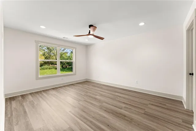 an empty room with wooden floor chandelier and windows