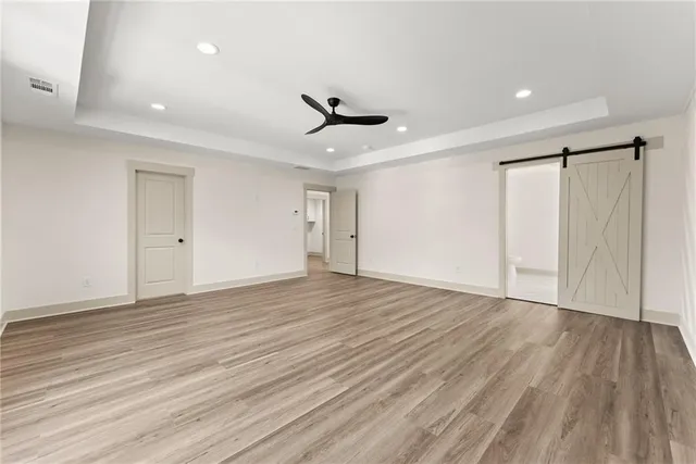 a view of an empty room with wooden floor and a ceiling fan