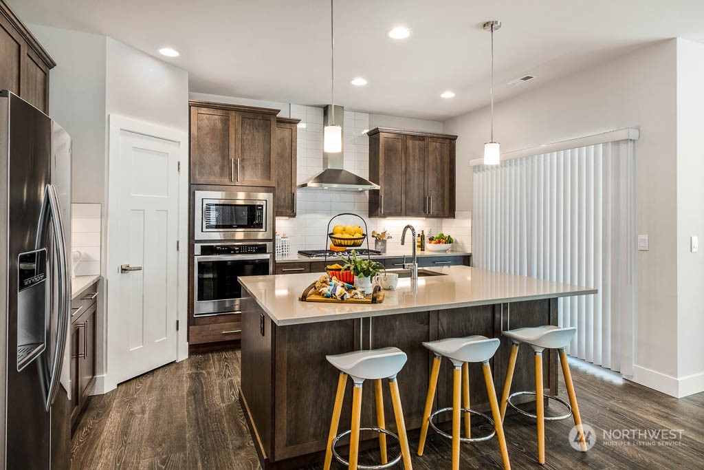 21535 6th Drive Southeast, Unit RM15 Bothell, WA 98021 - Photo 25 of 26 a kitchen with stainless steel appliances kitchen island granite countertop a dining table chairs refrigerator and sink