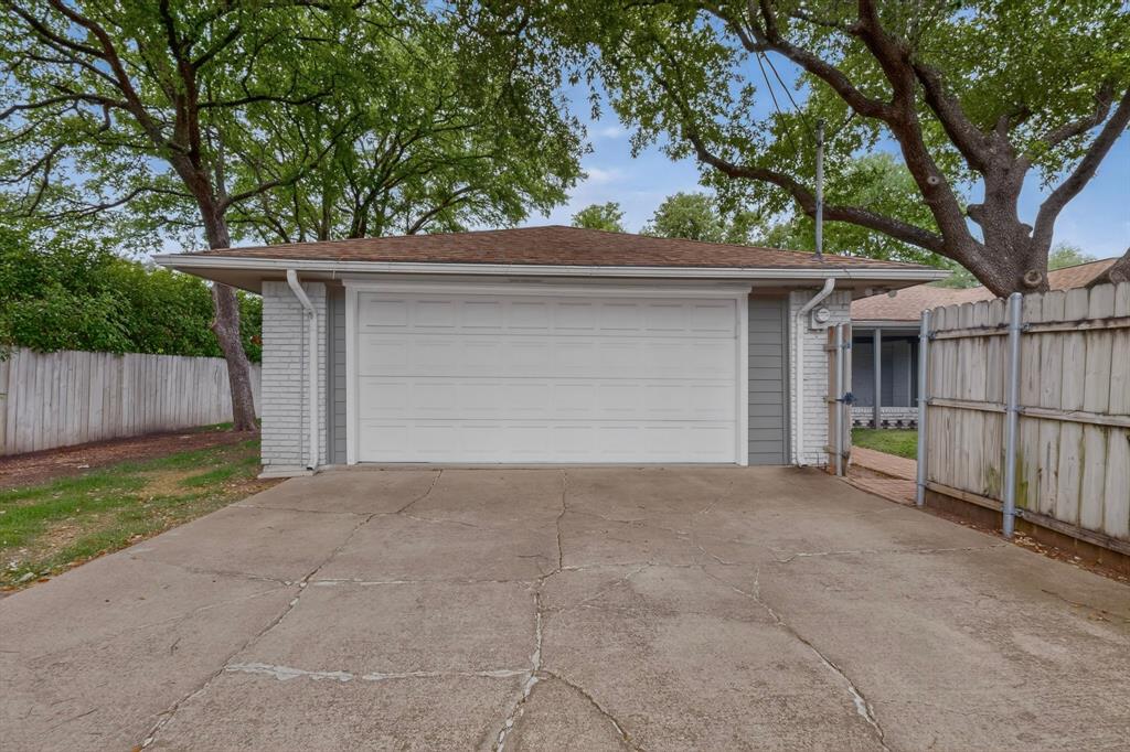 7631 Meadow Road Dallas, TX 75230 - Photo 40 of 40 A wide driveway leading to the spacious garage surrounded by a fence
