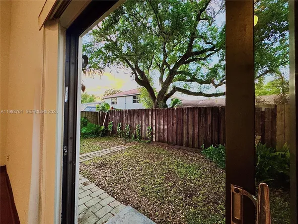 a view of a backyard with large trees and wooden fence
