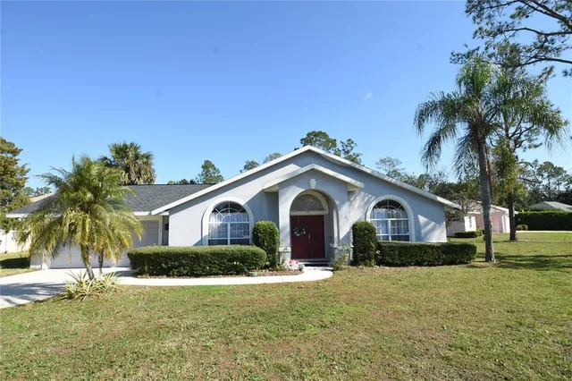 a front view of a house with a garden and palm trees