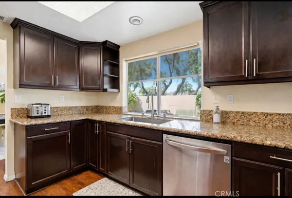 a kitchen with granite countertop stainless steel appliances a sink stove and cabinets