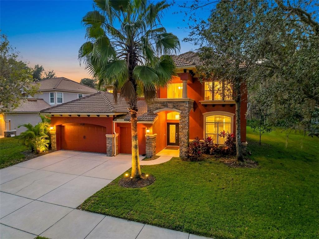 a front view of a house with a yard and palm trees