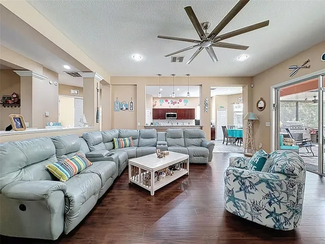 a kitchen with stainless steel appliances kitchen island granite countertop a refrigerator a sink a stove and a dining table with wooden floor