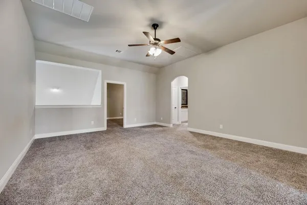 an empty room with chandelier fan and windows