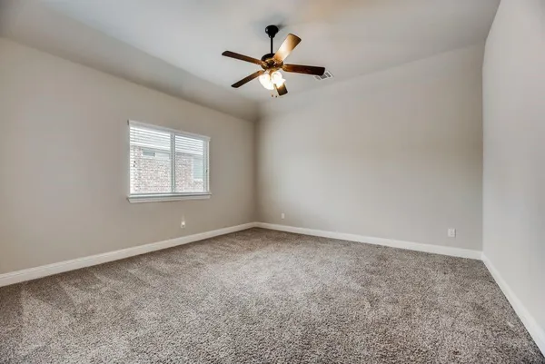 an empty room with ceiling fan and window
