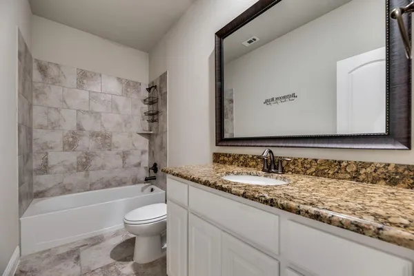 a bathroom with a granite countertop sink a toilet and a bathtub