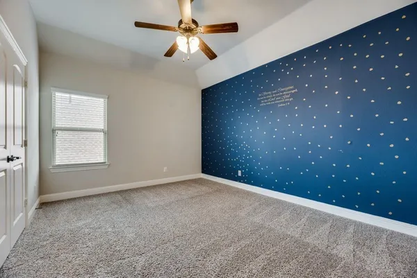 an empty room with a chandelier fan and windows