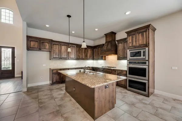 a kitchen with kitchen island granite countertop a stove oven and a sink with granite countertops