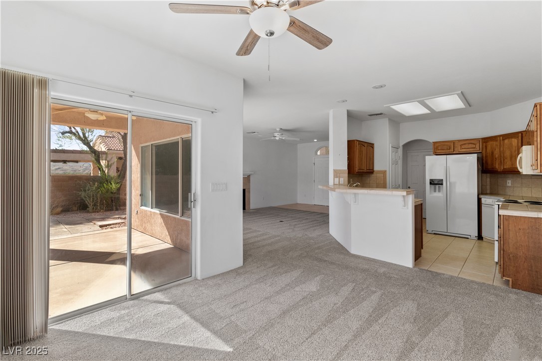 1200 Golf Club Drive Laughlin, NV 89029 - Photo 12 of 87 Kitchen with tasteful backsplash, ceiling fan, light carpet, white appliances, and brown cabinetry