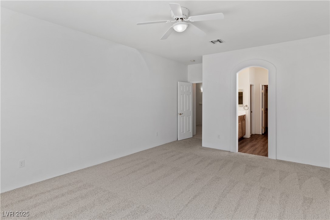 1200 Golf Club Drive Laughlin, NV 89029 - Photo 24 of 87 Primary bedroom featuring carpet floors, arched walkways, connected bathroom, and ceiling fan