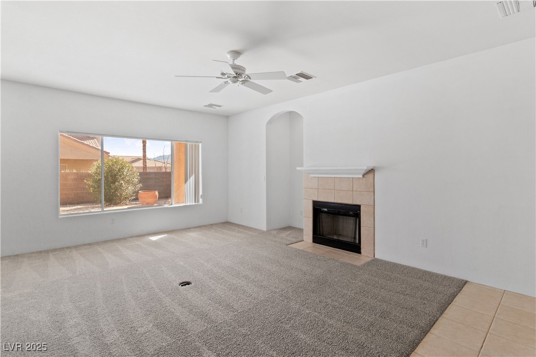 1200 Golf Club Drive Laughlin, NV 89029 - Photo 8 of 87 living room with a tiled fireplace, ceiling fan, arched walkways, and light colored carpet