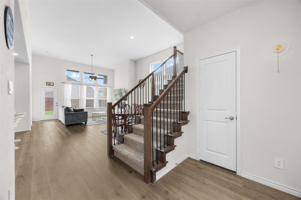 3808 High Country Road Aubrey, TX 76227 - Photo 20 of 36 Open-concept living area featuring high ceilings, wood-finish flooring, and a contemporary staircase with carpeted treads and wrought iron spindles