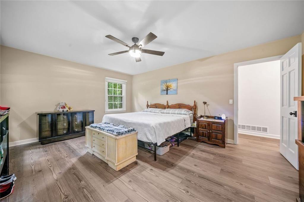 286 Hilton Way Canton, GA 30114 - Photo 23 of 59 a spacious bedroom with a bed a dresser and wooden floor