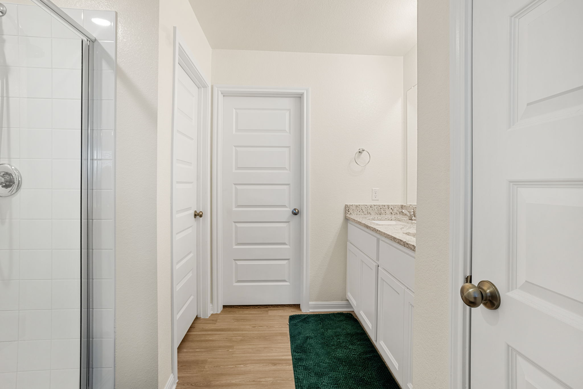 148 Hidalgo Lane Elgin, TX 78621 - Photo 26 of 38 A well-lit bathroom features a white tiled shower and a vanity with granite counters.