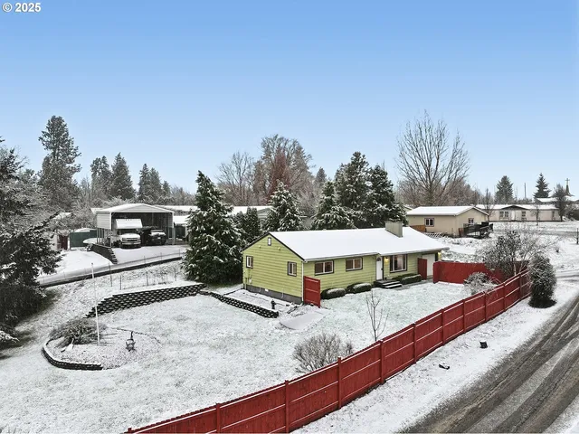 a view of a house with yard and trees in the background