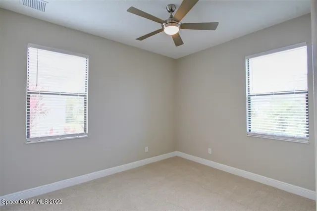 an empty room with a window and a fan