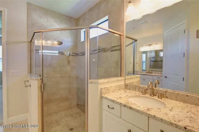 a bathroom with a granite countertop sink mirror and shower