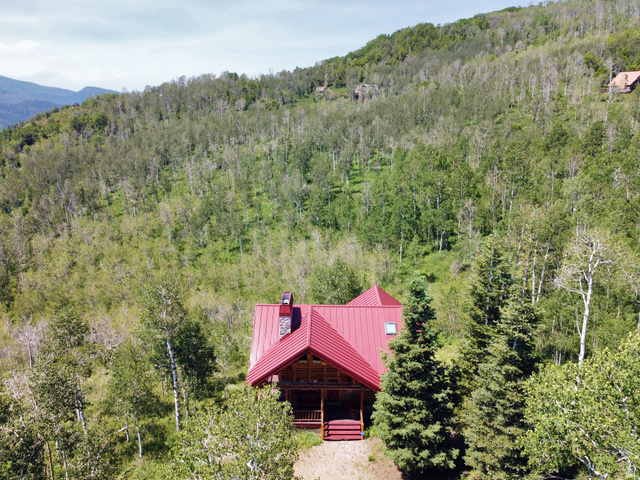 6210 Mountain View Road, Unit 133 Coalville, UT 84017 - Photo 3 of 87 The cabin has a vibrant red metal roof and chimney cap, a stone-clad chimney, and a covered porch.
