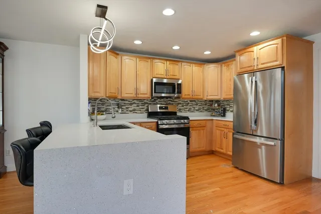 a kitchen with granite countertop a refrigerator a stove top oven a sink and dishwasher