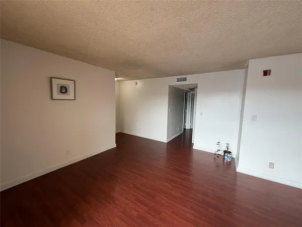 a view of an empty room with wooden floor and closet