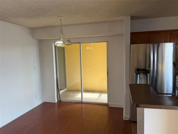 a view of a kitchen with a refrigerator and wooden floor