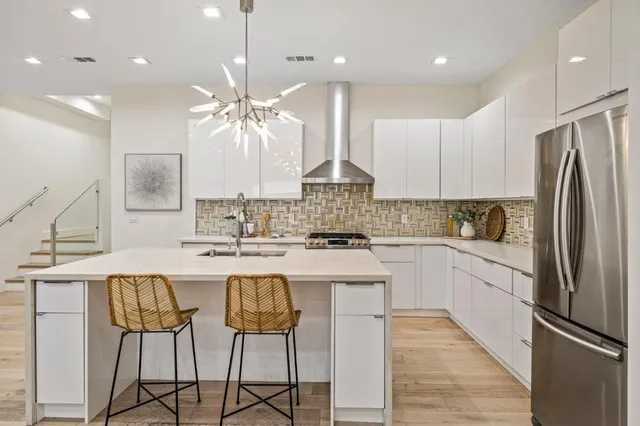 a kitchen with stainless steel appliances granite countertop a sink a stove a refrigerator and island with wooden floor