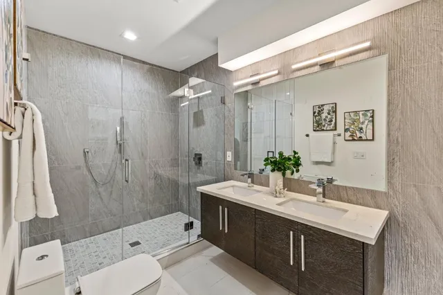 a bathroom with a double vanity sink toilet mirror and shower