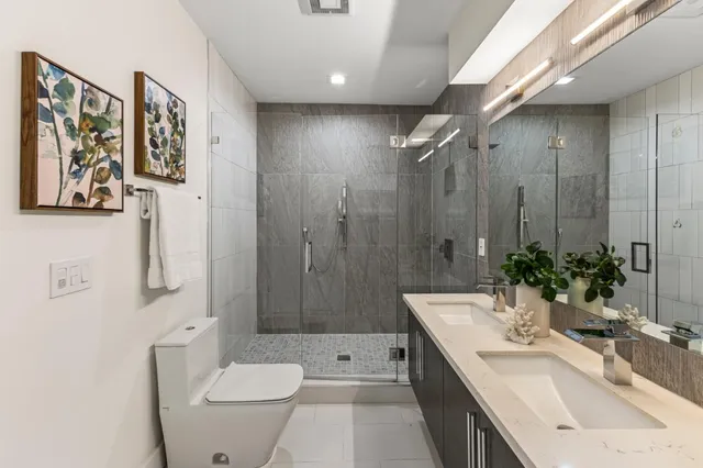 a bathroom with a double vanity sink toilet and shower