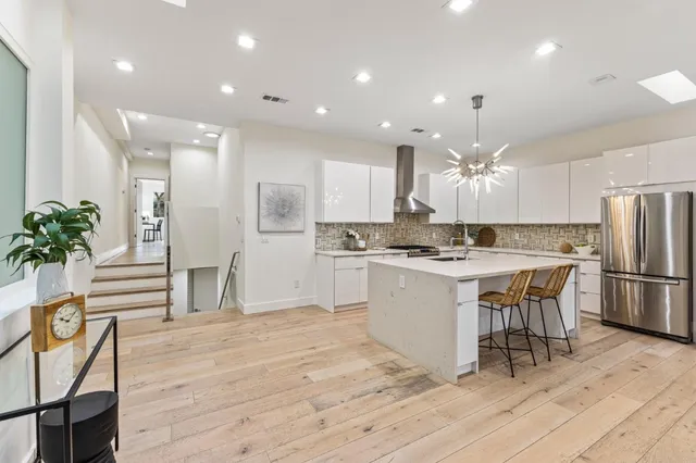 a large kitchen with kitchen island white cabinets and stainless steel appliances