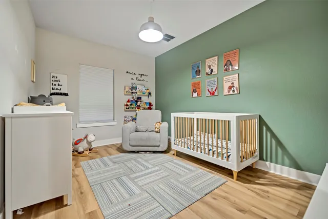a bedroom with baby crib and a wooden floor