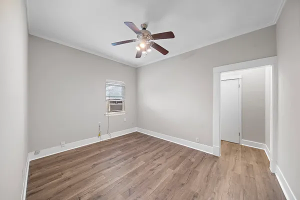 a view of an empty room with wooden floor and a ceiling fan
