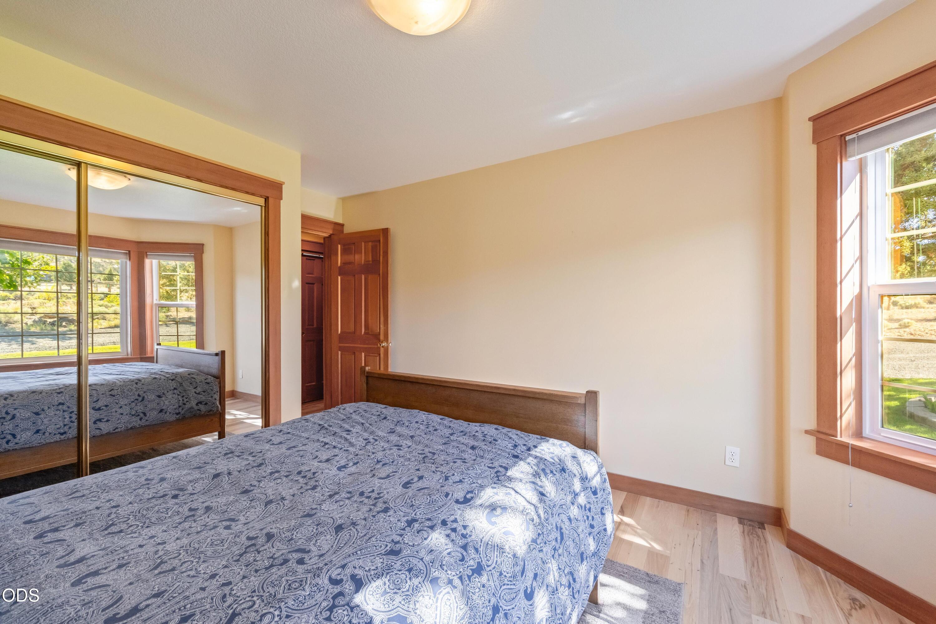 13753 South Sego Lily Road Powell Butte, OR 97753 - Photo 14 of 46 a bedroom with a large bed and wooden floor