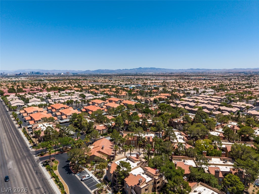 9325 West Desert Inn Road, Unit 244 Las Vegas, NV 89117 - Photo 50 of 55 An aerial perspective reveals a vast community of homes under a bright desert sky, extending toward distant mountains.
