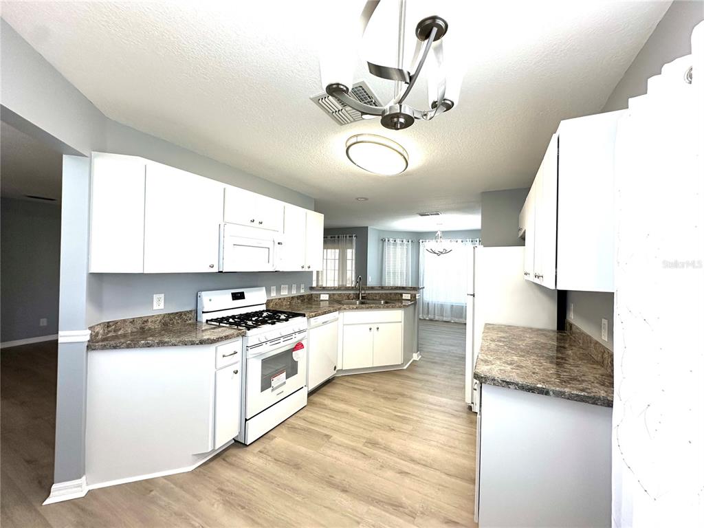 9706 Southwest 92nd Place Road Ocala, FL 34481 - Photo 7 of 82 a kitchen with a stove a sink and white cabinets with wooden floor