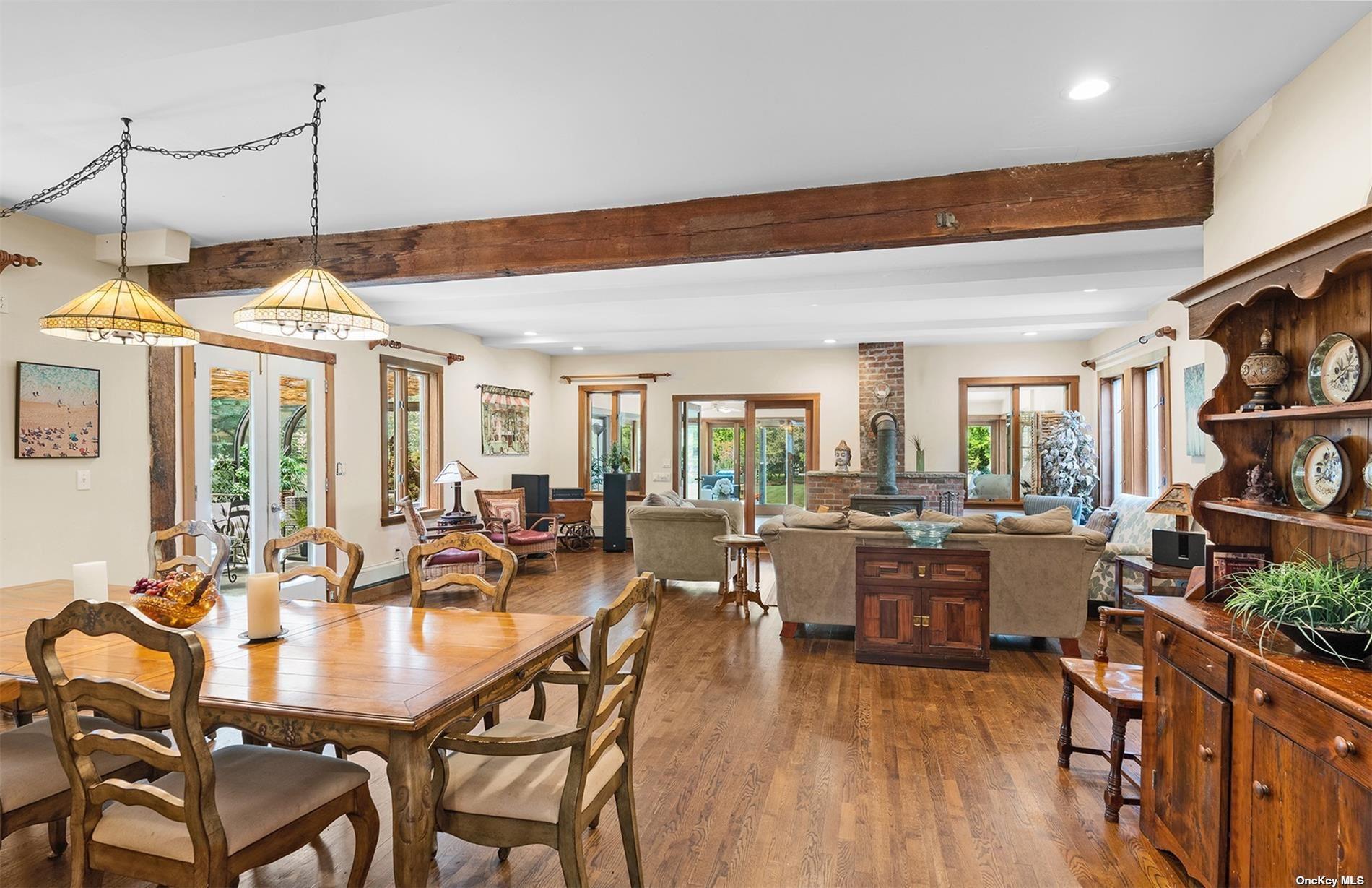 61 Lower 7 Ponds Road Water Mill, NY 11976 - Photo 12 of 43 a view of a dining room and livingroom with furniture wooden floor a rug a painting and a chandelier