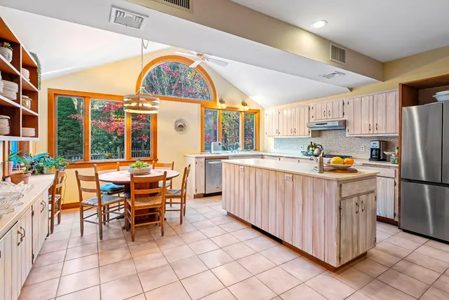 a kitchen with stainless steel appliances granite countertop a table chairs a refrigerator and a stove