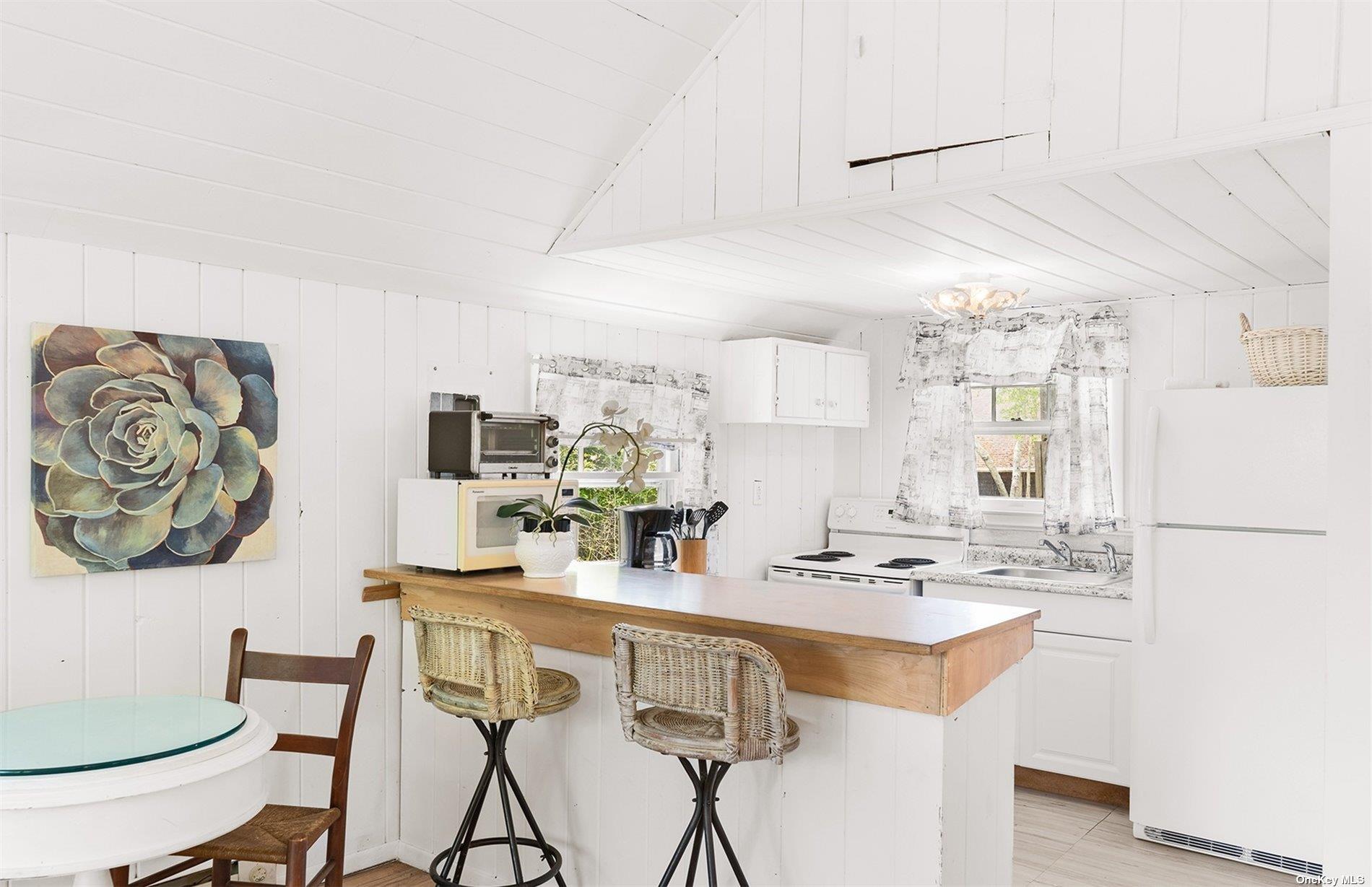 61 Lower 7 Ponds Road Water Mill, NY 11976 - Photo 40 of 43 a kitchen with stainless steel appliances a white table chairs and a refrigerator