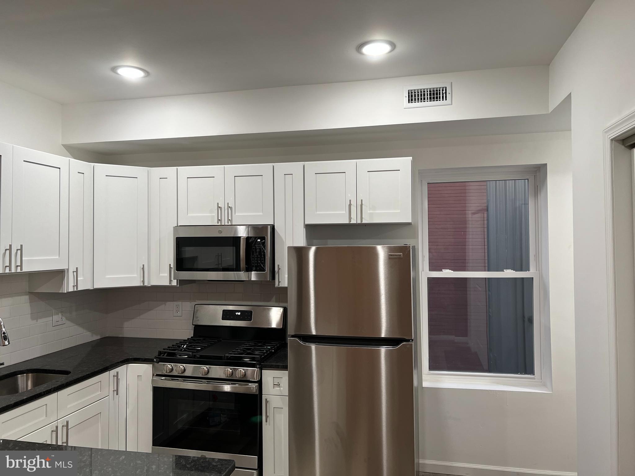 2814 Master Street, Unit B Philadelphia, PA 19121 - Photo 5 of 13 a kitchen with a refrigerator a stove top oven a sink and cabinets